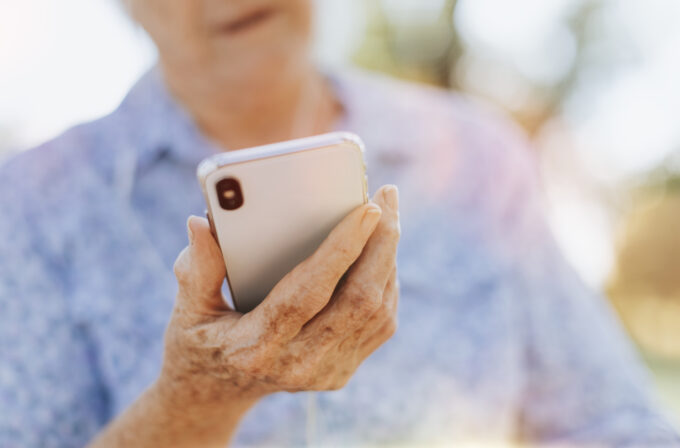 Senior woman using her phone in a park with Chat Yourself